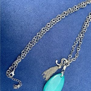 Silver colored necklace with large aqua colored stone, letter S & silver tassel